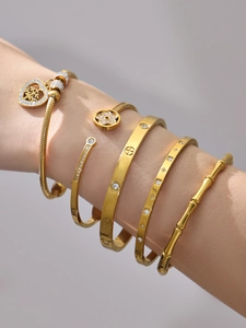 Dettaglio di bracciali sovrapposti placcati oro 18k con trama a bambù e zirconi