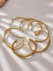 Detail van diverse gouden open armbanden met bamboe en gedraaide texturen met schaduweffect
