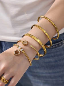 Dettaglio di bracciali e anello in acciaio inossidabile placcato oro 18k su una modella