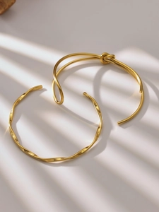 Detail van gouden knoop- en golvende armbanden onder artistiek spel van licht en schaduw