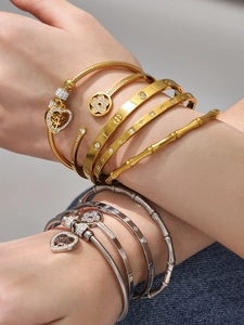 Dettaglio di bracciali sovrapposti in oro e argento con zirconi e trama bamboo