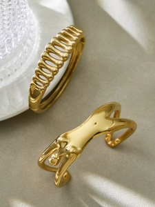 Dettaglio macro di bracciali artistici in oro a forma di spina di pesce e busto femminile