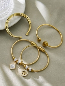 Dettaglio del set di quattro bracciali in acciaio inossidabile dorato con ciondoli