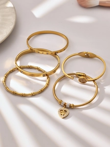 Dettaglio di bracciali in acciaio placcati oro 18k con zirconi e design a bambù