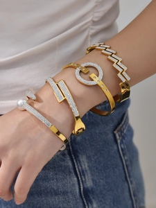 Gros plan de quatre bracelets dorés sertis de zircons 5A et d'une perle au poignet