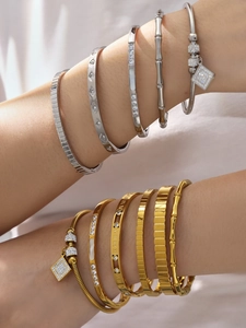 Detalle de brazaletes bañados en oro de 18k con circonitas y números romanos