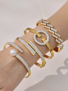 Détail d'un ensemble de bracelets en acier doré 18 carats avec zircons sur un poignet