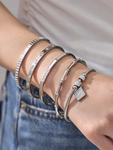 Primer plano de conjunto de pulseras y brazaletes de plata con circonitas y texturas