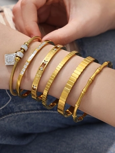 Detalle de cinco brazaletes bañados en oro de 18k con circonitas y números romanos