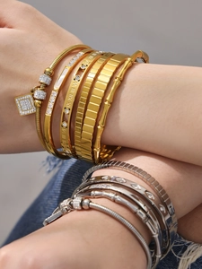 Detalle de pulseras de oro de 18k con circonitas y grabado de números romanos
