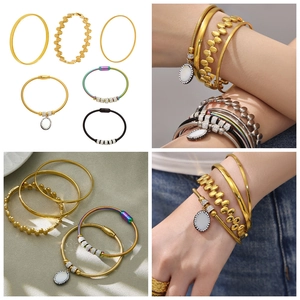 Detailansicht eines 5-teiligen goldenen Armband-Sets mit Kristall- und Muschelanhängern