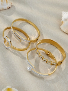 Détail de joncs en acier plaqué or 18k avec zircon 5A et perle sur sable fin de plage