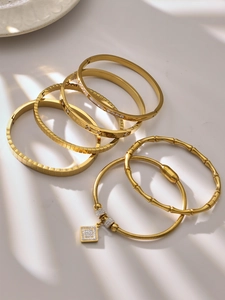 Detalle del conjunto de brazaletes de acero chapado en oro 18k con circonitas y números romanos