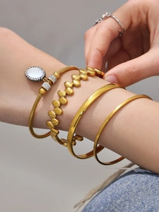 Detail von goldenem Armreif-Set mit Kristall-Anhänger und strukturierten Armbändern