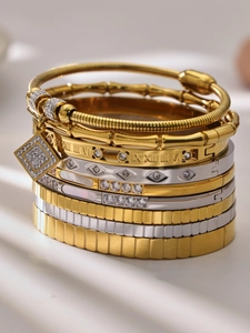 Detalle macro de brazaletes de acero bañados en oro 18k con números romanos y circonitas