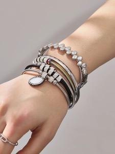 Detail von geschichteten Silberarmbändern mit Strasssteinen und Magnetverschluss am Handgelenk