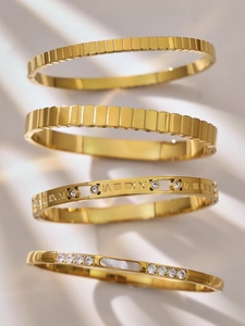 Detalle de brazaletes bañados en oro de 18k con números romanos, circón y nácar
