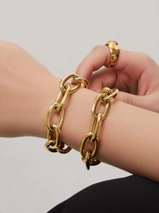 Nahaufnahme eines klobigen vergoldeten Kettenarmbands und passenden Rings am Handgelenk
