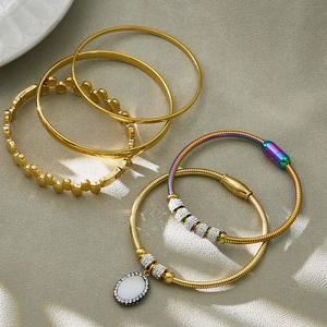 Fünfteiliges goldenes Edelstahl-Armbandset mit Strass-Anhängern auf grauem Hintergrund