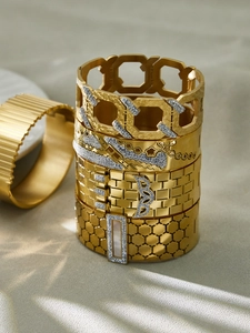 Close-up of stacked gold-plated honeycomb and textured bangles with cubic zirconia stones