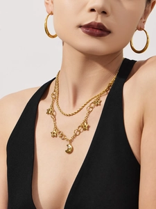 Gros plan du collier doré étoile et lune avec boucles d'oreilles créoles sur modèle
