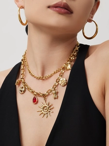 Detail of gold necklace set featuring bear pendants and red teardrop gems on model