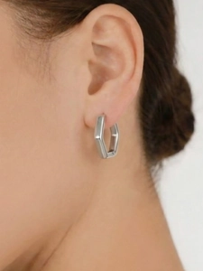 Nahaufnahme eines silbernen geometrischen sechseckigen Ohrrings für einen minimalen Look