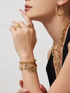 Close-up of gold-plated jewelry set with sun, bear charms and red zircon teardrop pendant