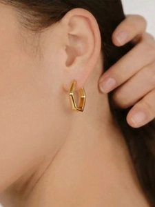Nahaufnahme der goldenen sechseckigen Creolen am Modell mit glänzendem Edelstahl-Finish
