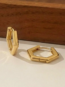 Detailaufnahme der geometrischen sechseckigen Gold-Ohrringe auf einem Holzhintergrund