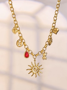 Detail of gold chain necklace with sun, heart, red gemstone, and diamond bear charms