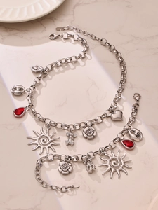 Detail of silver multi-pendant necklace and bracelet with red zircon drop on marble surface