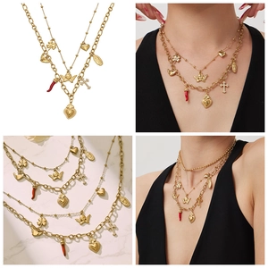 Detail of layered gold-plated necklaces featuring heart, angel, and clover charms