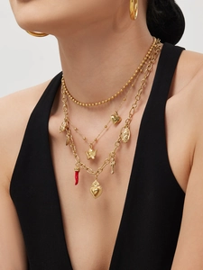 Detail of layered gold necklaces with heart and cross charms and large hoop earrings