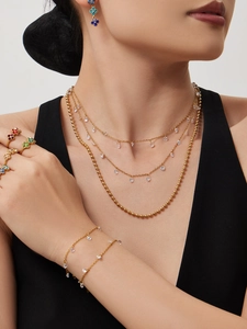 Details von mehrlagiger goldener Quastenkette mit Zirkonia und bunten floralen Ringen