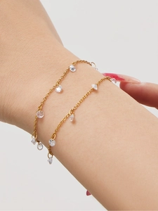 Detail von Quasten-Armband aus 18k vergoldetem Edelstahl mit Zirkonia-Anhängern am Handgelenk