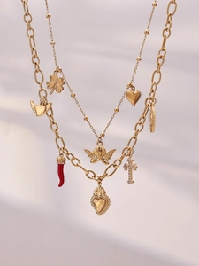 Detail of layered gold-plated necklaces with charms like holy heart and clover