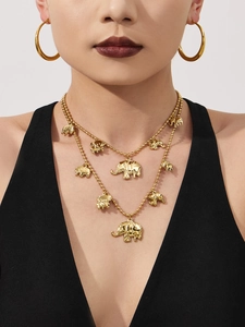Detailopname van een model met een dubbele gouden olifant hanger ketting en grote ronde ringen