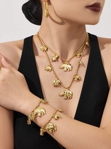 Detail van gelaagde gouden olifant halsketting en armband set op een model