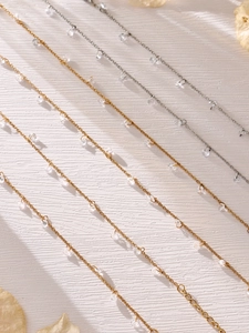 Makro-Detail von Gold- und Silbertaschel-Halsketten mit 5A-Zirkonia auf Texturoberfläche