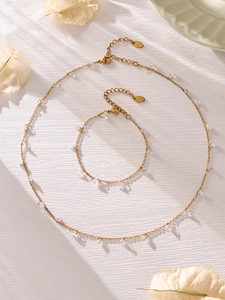 Detailaufnahme von vergoldetem Edelstahl Halsketten und Armband Set mit Zirkon-Anhängern