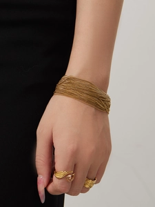 Detail van een gouden meerlaagse armband en een reliëfring met een druppelvormige steen