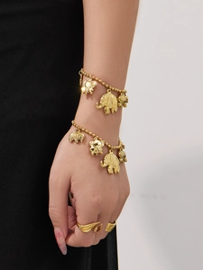 Detailopname van een gouden olifant bedelarmband en kristallen ring om de pols