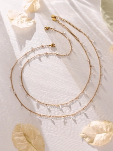 Detail der 18k vergoldeten Kette mit funkelnden 5A Zirkon-Quasten auf weißer Textur