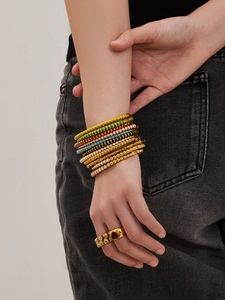 Gestreifte Emaille-Perlenarmbänder und goldener Herzring an Model in Jeans-Optik