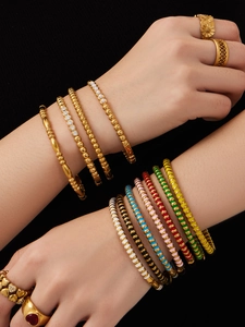 Nahaufnahme von goldenen geometrischen Armbändern mit bunter Emaille und Zirkonia