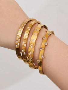 Detailed view of four luxury 18k gold plated stainless steel bangles with white zircon stones