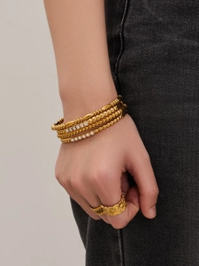 Makroansicht goldener Perlenarmbänder mit Zirkonia und Perlen sowie Sonnenblumenring