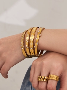 Close-up of stacked 18k gold plated geometric bangles and rings with zircon details