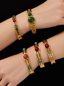 Dettaglio di bracciali vintage dorati con motivi traforati e pietre preziose colorate
